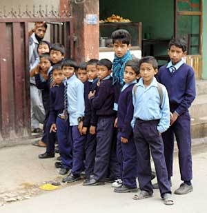 Kinder in Schuluniform warten vor dem Hoftor.