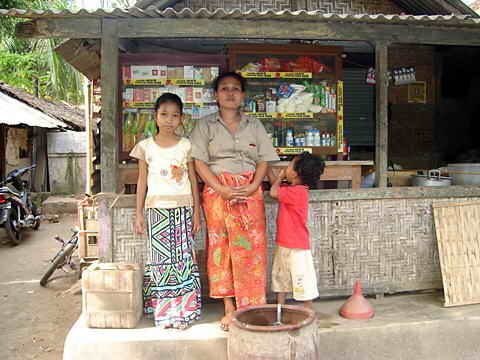 Frau mit ihren zwei Kindern vor einem kleinen Geschäft.