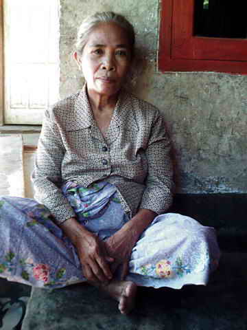 Ältere Frau sitzt auf der kleinen Veranda ihres Hauses.